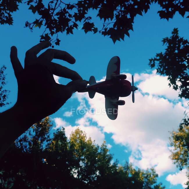 Vue en angle bas de la main d'une femme tenant un avion jouet — Photo de stock