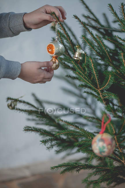 Imagen recortada de Niño decorando un árbol de Navidad - foto de stock