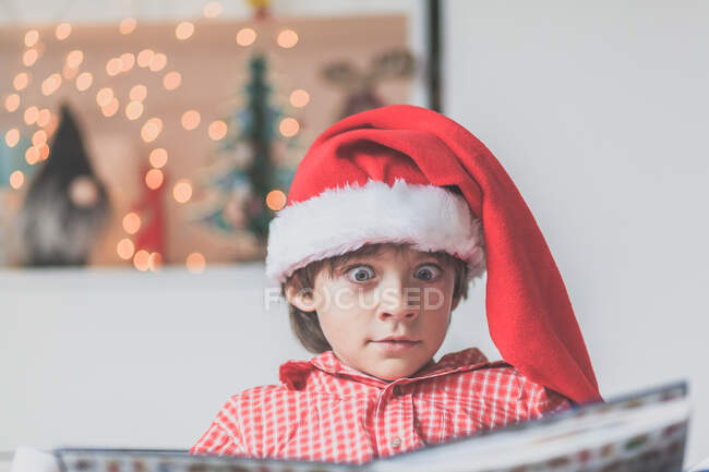 Retrato de un niño leyendo en un sombrero de navidad - foto de stock