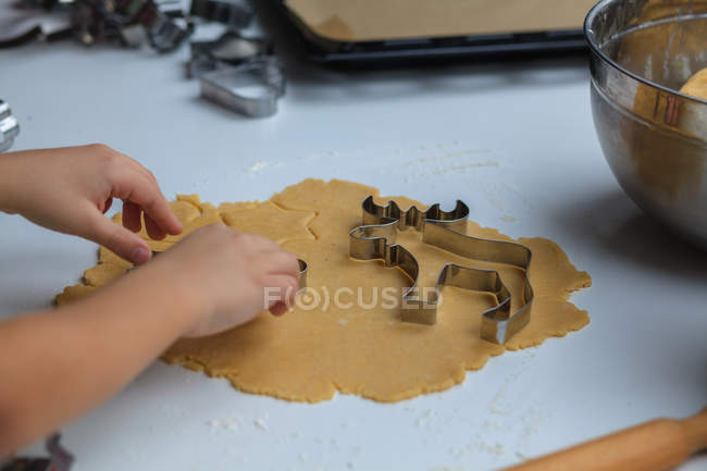 Imagen recortada de manos de niño haciendo galletas de Navidad - foto de stock