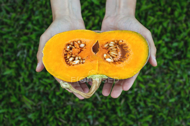 Man hands holding a halved pumpkin — Stock Photo