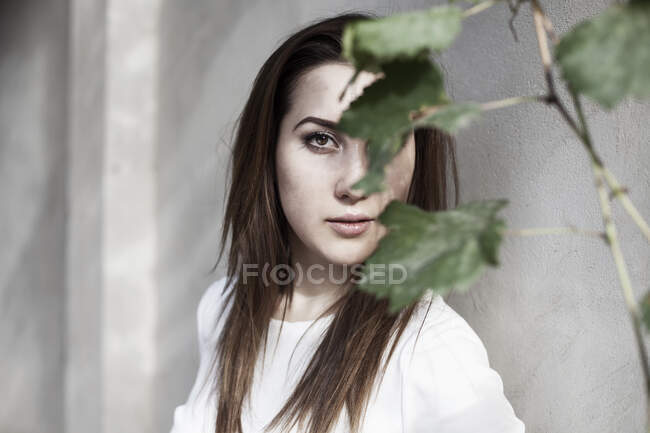 Retrato de una mujer con la cara oscurecida por hojas - foto de stock