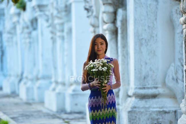 Jeune femme tenant des fleurs à l'extérieur du temple, Mandalay, Myanmar — Photo de stock