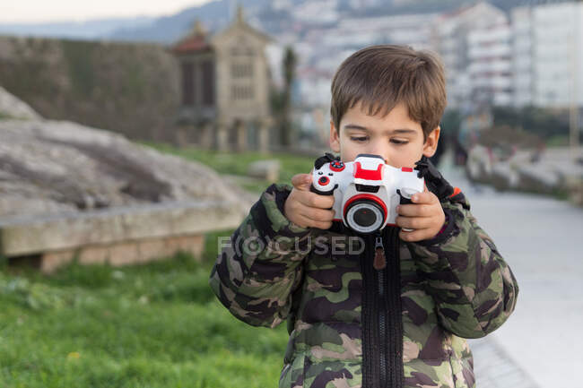 Menino com câmera de brinquedo de plástico ao ar livre — Fotografia de Stock