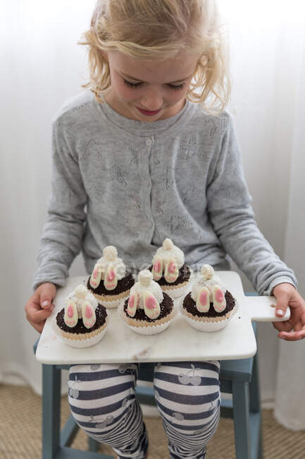 Girl holding bunny rabbit cupcakes — Stock Photo