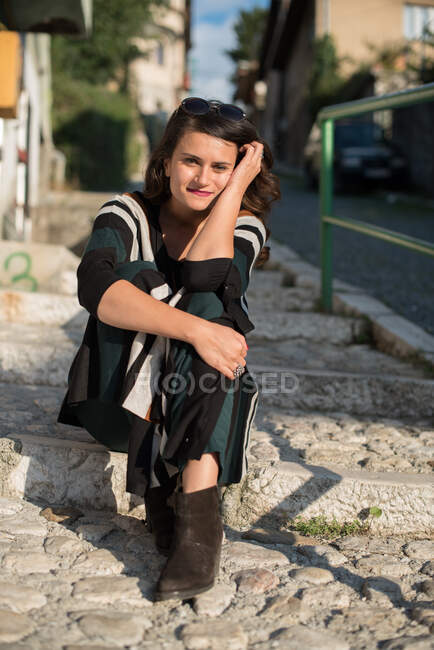 Giovane donna seduta su gradini in strada — Foto stock
