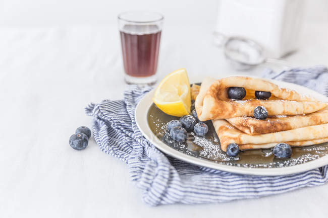 Pancakes with maple syrup and blueberries over table — Stock Photo