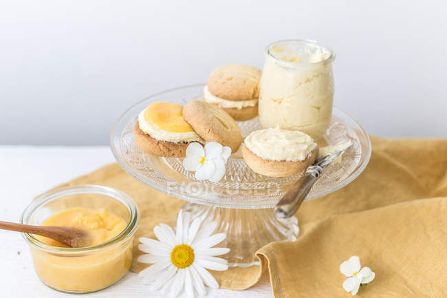 Pot of homemade lemon curd with melting moment biscuits and lemon buttercream — Stock Photo