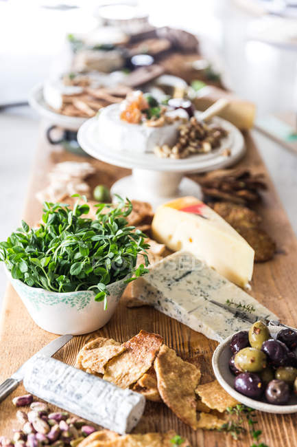 Formaggi, olive, noci e cracker su un tavolo — Foto stock