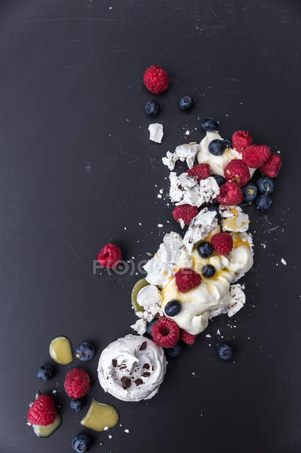 Deconstructed Pavlova and mixed berries over dark background — Stock Photo