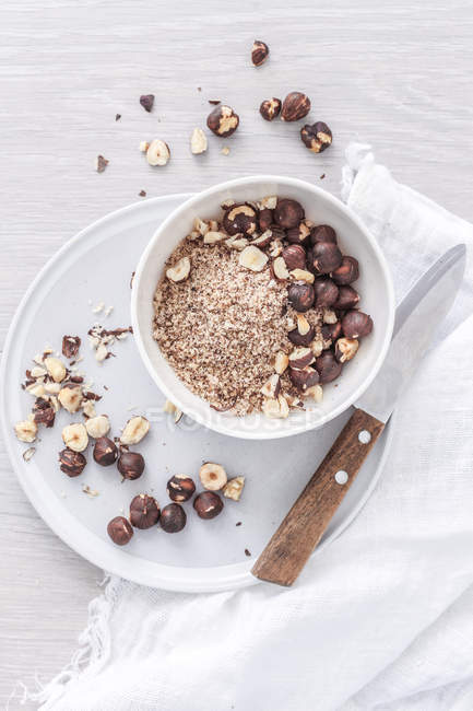 Whole, ground and chopped hazelnuts in bowl, top view — Stock Photo