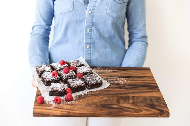 Frau hält Schneidebrett mit Brownies — Stockfoto