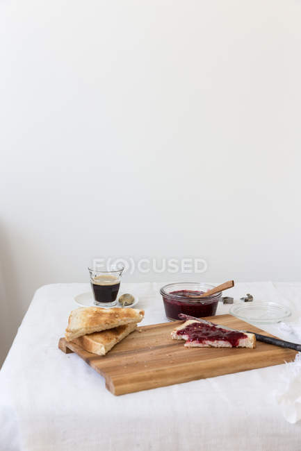 Toast and jam with coffee over chopping board at kitchen — Stock Photo
