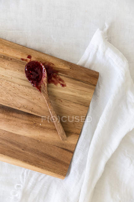 Wooden spoon covered in jam on chopping board — Stock Photo