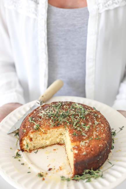 Woman holding Lemon and Thyme Syrup Cake with slice missing — Stock Photo