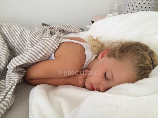 Красивая маленькая девочка, лежащая в постели, спит — стоковое фото