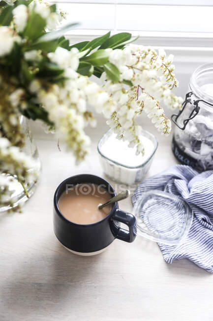 Closeup view of Cup of tea and vase of flowers — Photo de stock