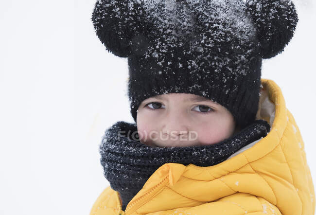 Retrato de um menino na neve vestindo roupas quentes — Fotografia de Stock