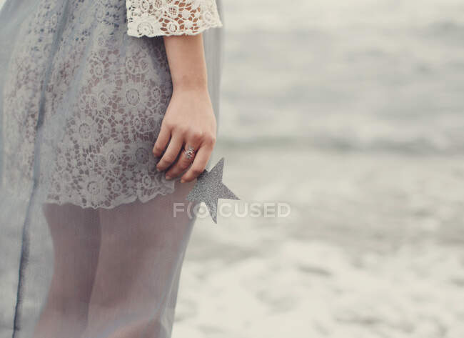 Donna in piedi sulla spiaggia con una stella in mano — Foto stock