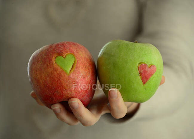 Woman holding Red and green apples with heart shapes missing — Stock Photo