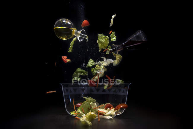 Вид крупным планом ингредиентов салата, падающих в миску — стоковое фото