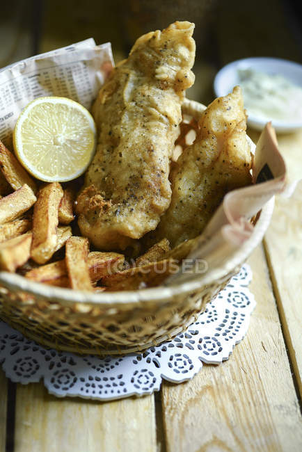 Cesto con pesce e patatine sopra tavolo di legno — Foto stock