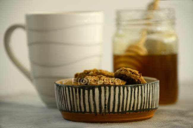 Galletas con una taza de té y miel, vista de cerca - foto de stock