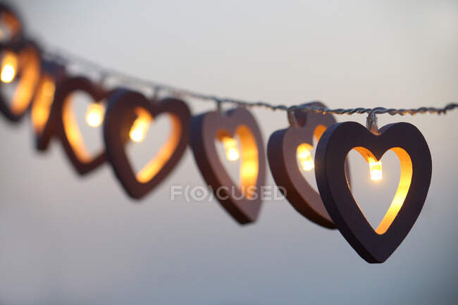 Luces de cuerda en forma de corazón colgando en una fila - foto de stock
