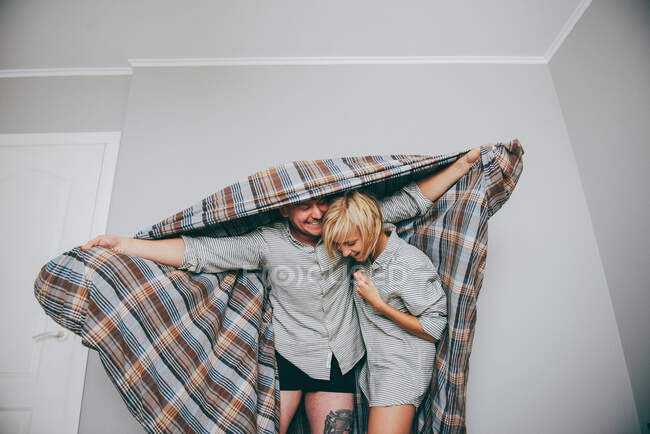 Homme et femme en train de jouer avec une courtepointe — Photo de stock