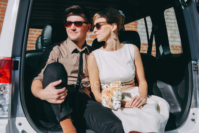 Пара сидящих в багажнике машины после свадьбы — стоковое фото