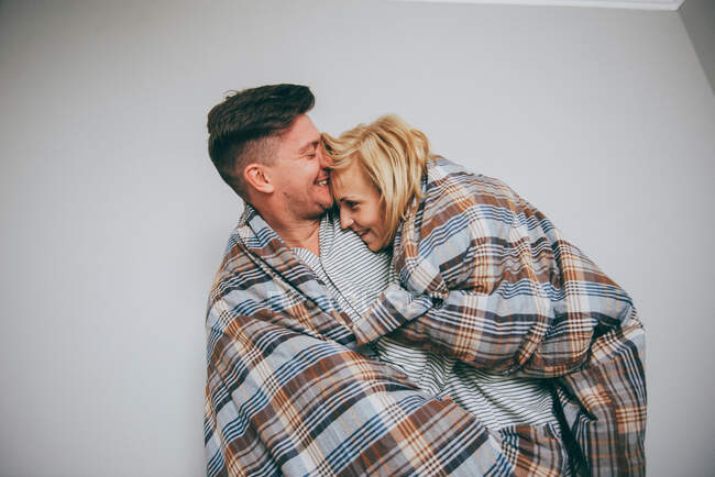 Man and woman cuddling in a quilt — Stock Photo