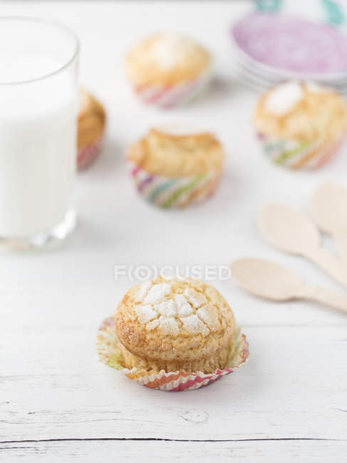 Closeup view of cupcakes with sugar and a glass of milk — Stock Photo