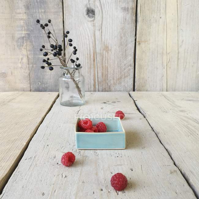 Bowl of fresh raspberries over wooden table — Stock Photo