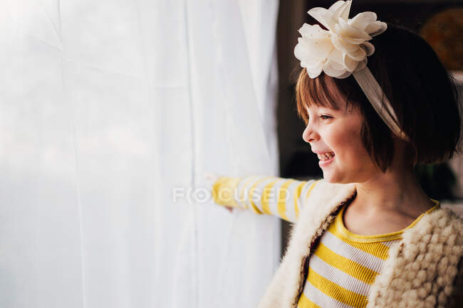 Souriante fille regardant par une fenêtre — Photo de stock