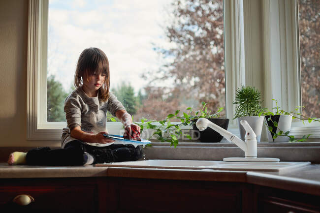Girl washing dishes in the kitchen sink — Stock Photo