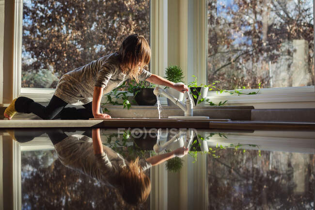 Girl sitting on kitchen counter turning on the tap — Stock Photo