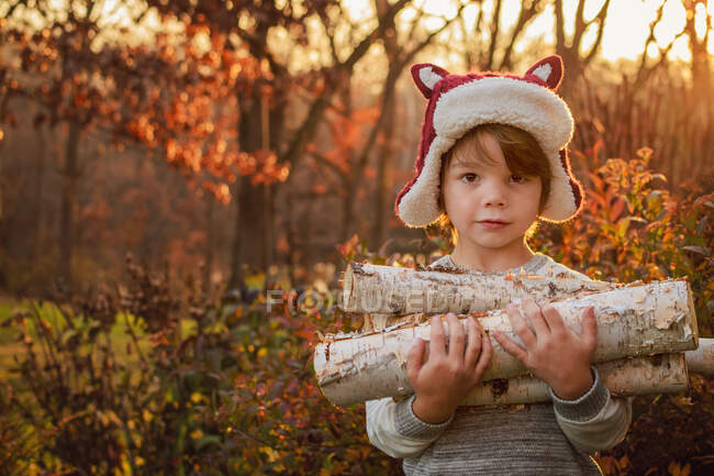 Ragazzo felice portando legna da ardere sulla natura — Foto stock