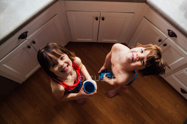 Menino e menina de pé na cozinha água potável — Fotografia de Stock