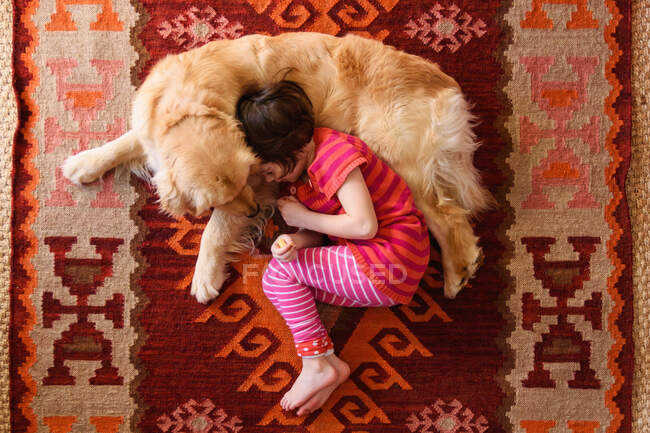 Vista aerea della ragazza sdraiata sul pavimento con un cane golden retriever — Foto stock