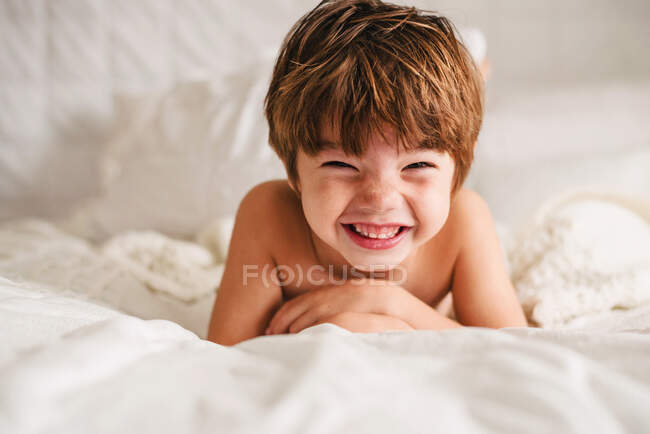 Ritratto di un ragazzo sorridente su un letto — Foto stock