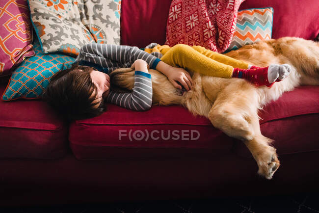 Girl sleeping on couch with golden retriever dog — Stock Photo