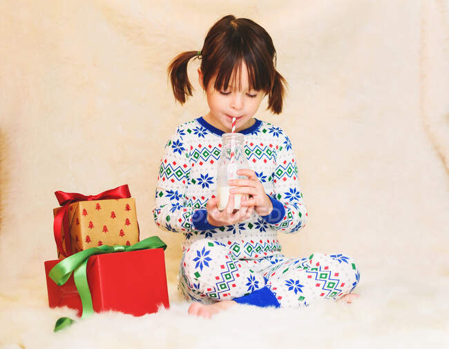 Fille avec cadeaux de Noël bouteille de lait à boire — Photo de stock