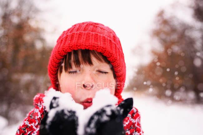 Menina soprando um punhado de neve — Fotografia de Stock