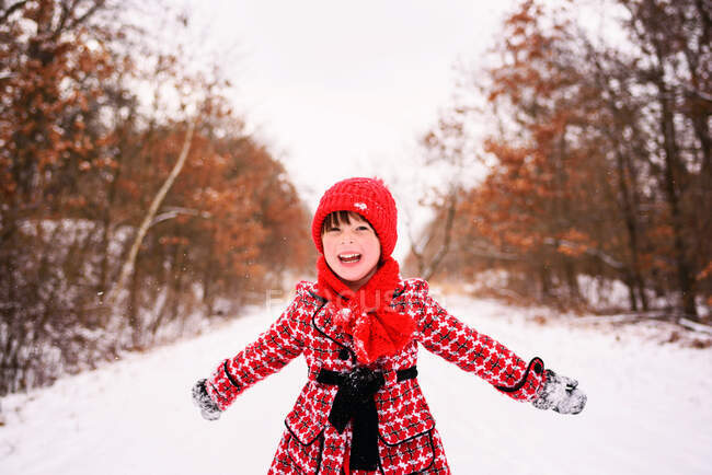 Girl standing in winter forest with arms outstretched — Stock Photo