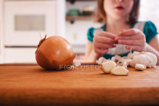 Girl peeling garlic cloves — Stock Photo
