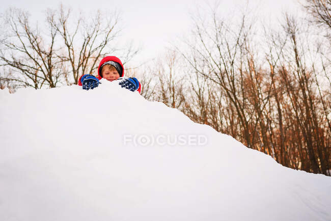 Menino brincando em cima de uma pilha de neve — Fotografia de Stock