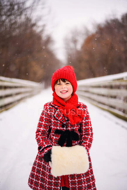 Menina de pé na ponte na neve com um muff de pele falsa — Fotografia de Stock