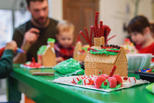 Family decorating gingerbread houses — Stock Photo