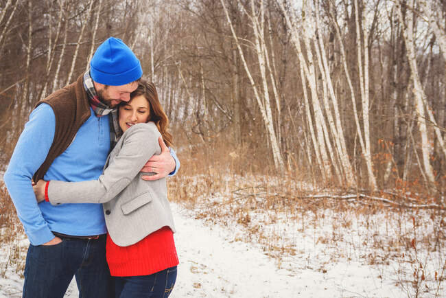 Uomo e donna in piedi in neve abbracci — Foto stock