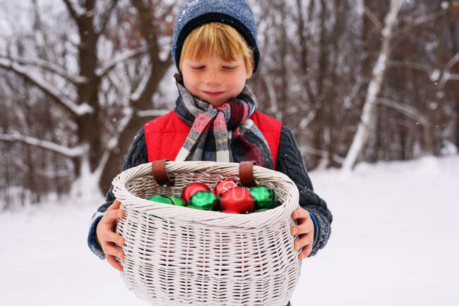 Garçon tenant panier rempli de décorations de Noël — Photo de stock